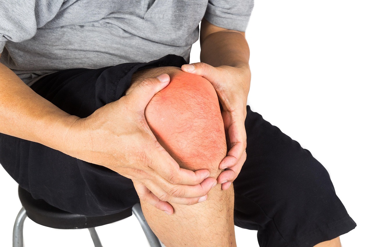 A person holding their painful knee joint due to inflammation